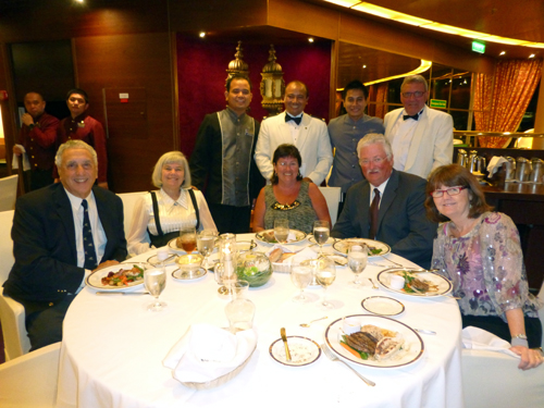 Ian Harkness (right, standing) takes advantage of his white dinner jacket to join wait staff in Rotterdam dining room. Seated at table are from left, Donald and Nancy Harrison of San Diego; Debbie and Greg Clarke of Grandview Lake, Saskatchewan, and Barbara Hoskins of Newbury, England