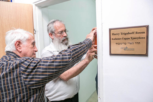 Philanthropist Harry Triguboff, foreground, helps as mezuzah is affixed to his documentation room by Rabbi Tzachi Lehman.