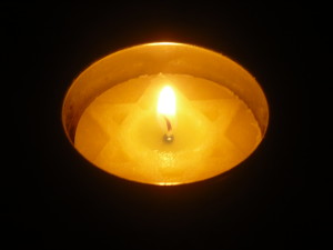 A lit Yom Hashoah candle in a dark room on Yom Hashoah.  (Photo by Valley2city. CC BY-SA 3.0 via Wikimedia Commons. http://commons.wikimedia.org/wiki/File:Yom_Hashoah_candle.jpg)