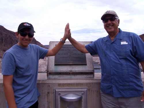 Hoover Dam straddles the Nevada-Arizona line. Here grandson Shor, in Nevada, highfives his grandfather, the writer, who is in Arizona
