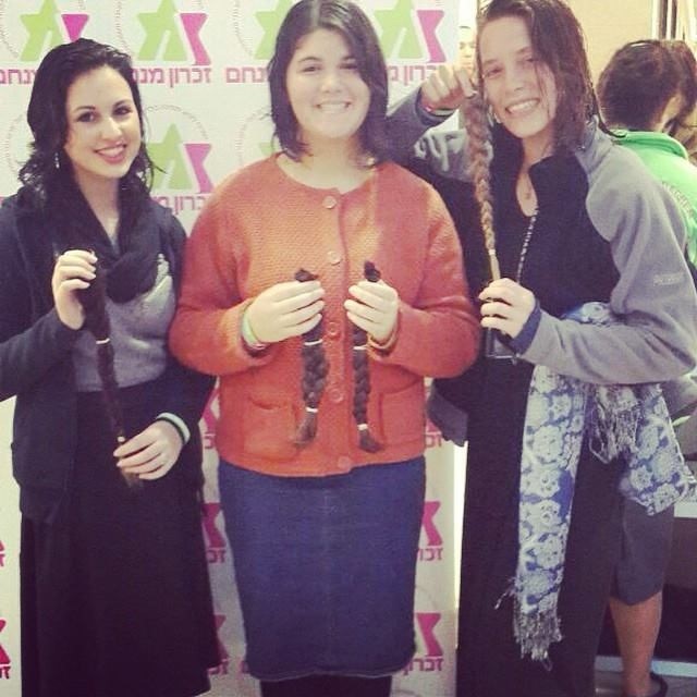 Donors show the braids cancer patients will receive. {Photo: Zichron Menachem}
