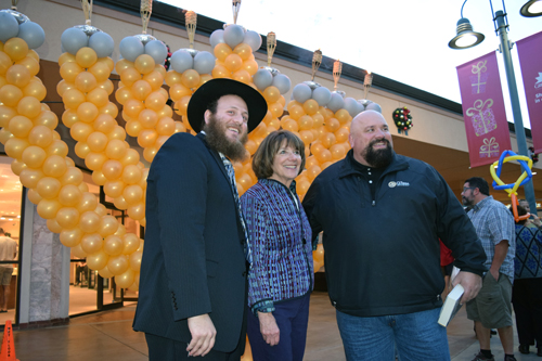 Rabbi Rafi Andrusier, Congresswoman Susan Davis, and La mesa Mayor Mark Arapostathis stand in front of large balloon menorah at Grossmont Shopping Center