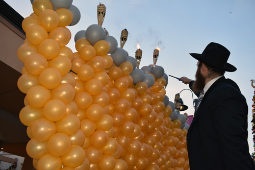 Rabbi Andrusier touches a lighter to a torch atop the menorah