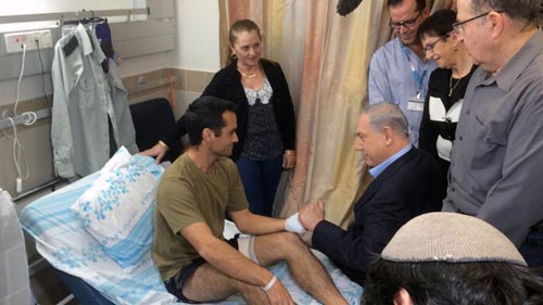 Benyamin Netanyahu sits with a wounded IDF soldier at the Rambam Health Care Center in Haifa