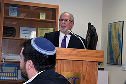 Rabbi Simcha Weiser lectures while in foreground Joshua Cohen readies a video for showing