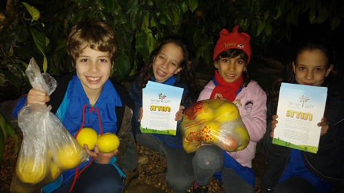 Israeli children with certificates and bags of fruit picked for distribution to the needy