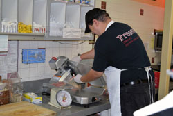 An employee slices some deli meat