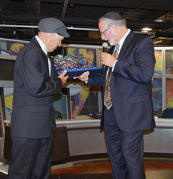 Rafa Guerrero, honored for the gardens he is teaching students to grow, is presented a commemorative menorah by Rabbi Simcha Weiser