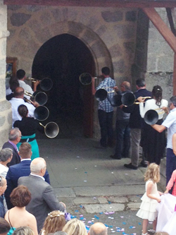 Musicians play hunting trombones outside church in celebration of the bride and groom