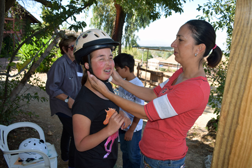 Samantha Yamamoto, right, adjusts riding helmet for her daughter, Alise. In background, Samantha's son, Ryan, confers with Catherine Hand