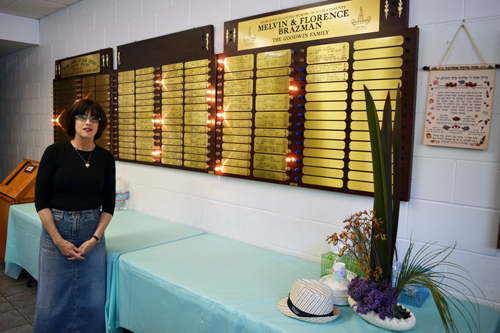 Julie Goodwin poses by memorial plaques in the cozy YISD social hall