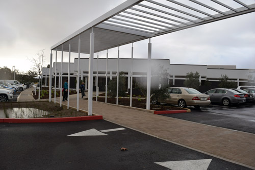 Trellised walkway connects new building in background with Turk Family Center at the Jacobs Family Campus