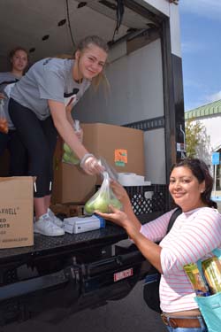 Maya Sharf, 14, hands fresh produce from a food truck to unidentified recipient. "The military is helping us so we should halep them too," she says.