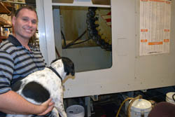 Peter Weinreb stands by the tool wheel of a computerized assembly that machines pumps to precise specifications. He is holding Oscar. Dogs are a common site at the plant as Peter's sister Rebecca heads the non-profit Animal Pad, an all-breed animal rescue service