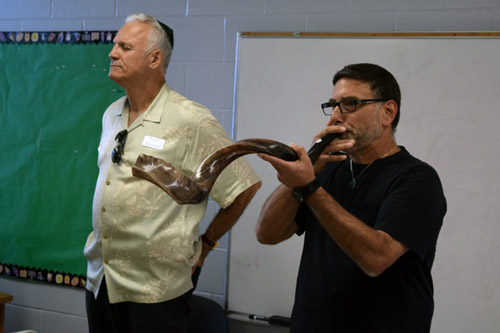 Rob Nosan demonstrates his technique for sounding the shofar. At his left is Jerry Hermes, president of Tifereth Israel Synagogue