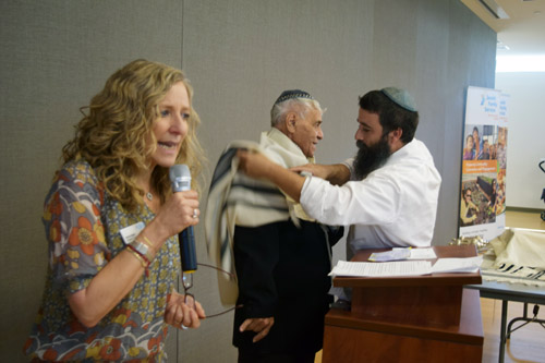 Aviva Saad, foreground, relates the circumstances leading up to Lazar Abramovitch's bar mitzvah, as Rabbi Moti Fradkin adjusts Abramovitch's tallit.