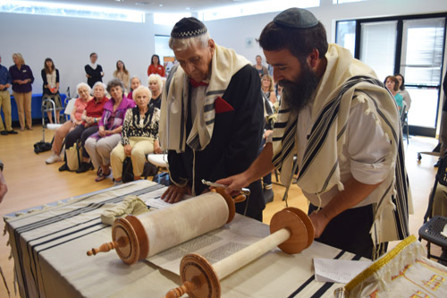 Rabbi Moti Fradkin unrolls a Torah as Lazar Abramovitch prepares to read the blessings